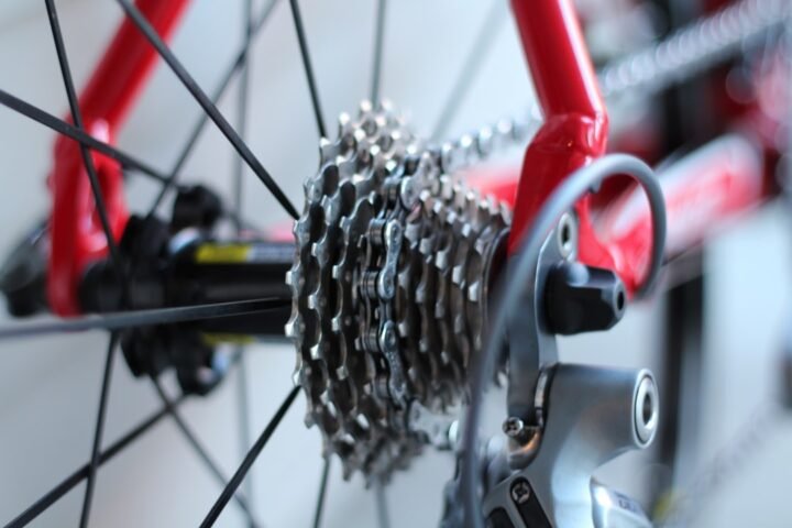 A close-up of a bicycle chain being inspected with tools in a workshop setting.