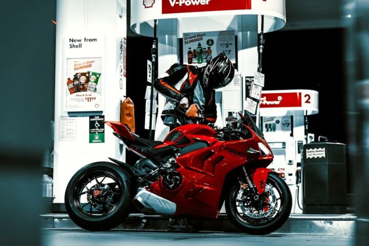 A mechanic inspecting motorcycle fluids with tools and a service manual in a garage setting.