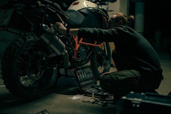 A close-up of a motorcycle tire with a focus on tread depth and wear indicators, set against a blurred background of a motorcycle.