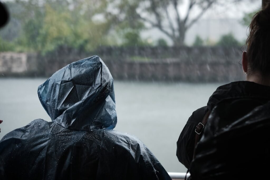A motorcyclist wearing waterproof rain gear riding in the rain, showcasing visibility and comfort in wet conditions.