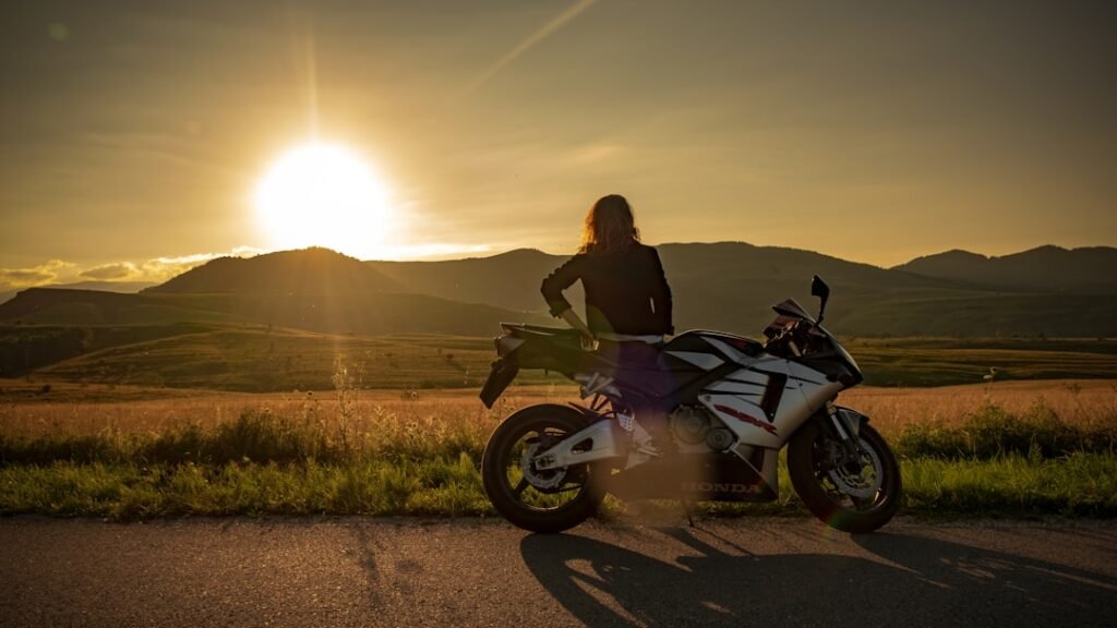 A confident rider wearing protective gear, riding a motorcycle on a scenic road, showcasing skill and focus.