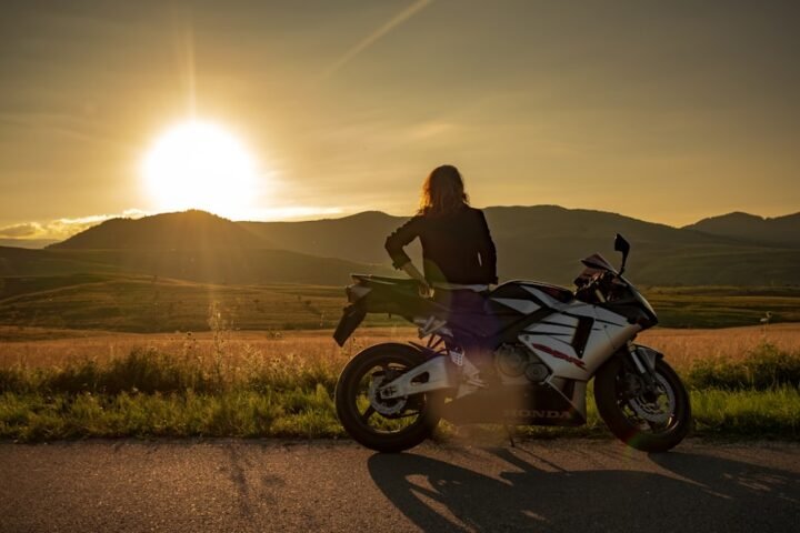 A confident rider wearing protective gear, riding a motorcycle on a scenic road, showcasing skill and focus.
