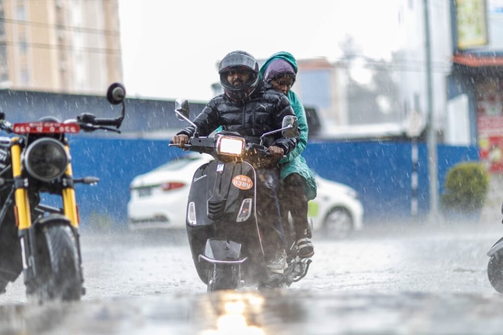 A motorcyclist navigating a wet road during rain, showcasing proper riding techniques and safety gear.