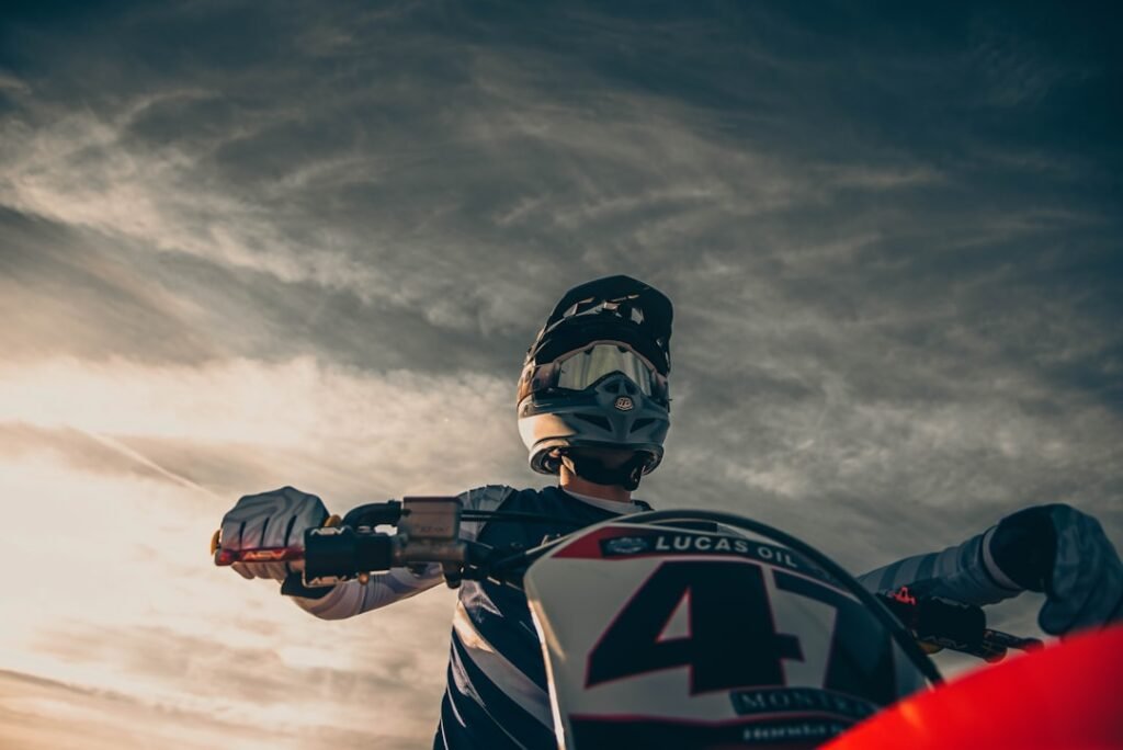 A motorcycle rider using an action camera while riding on a scenic road.