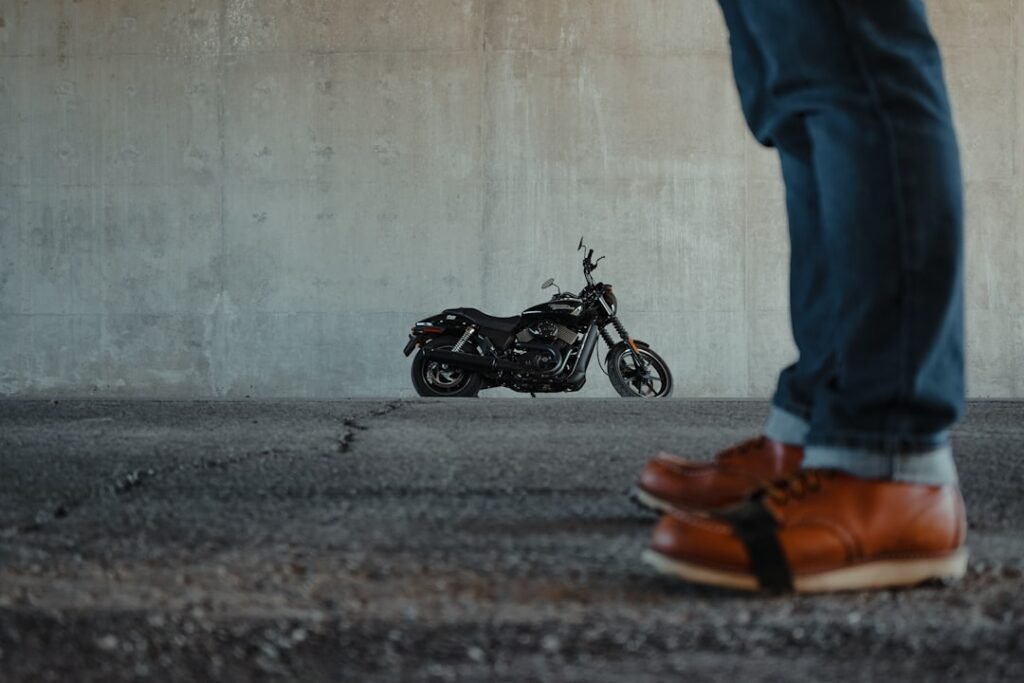 A close-up of a pair of sturdy motorcycle boots on a road, showcasing their design and durability.