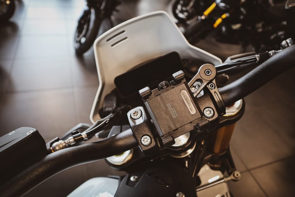 A motorcycle with a phone mount attached, showcasing a smartphone securely held in place while riding on a scenic road.