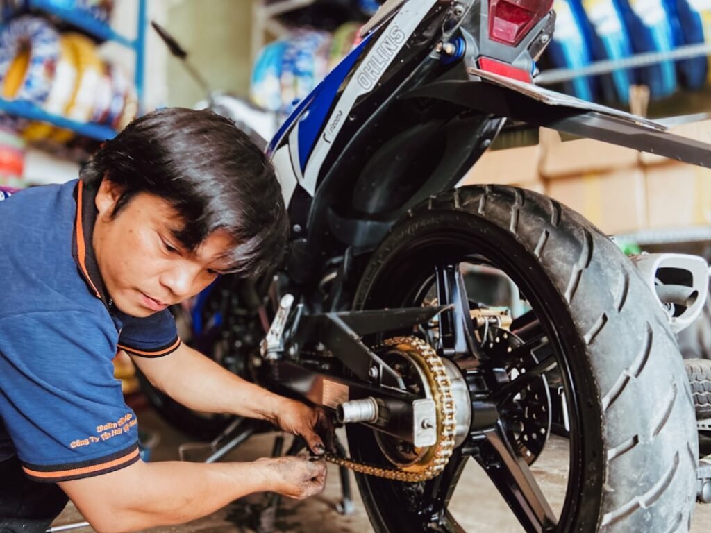 A close-up of a motorcycle tire on a road, showcasing tread patterns and wear indicators.