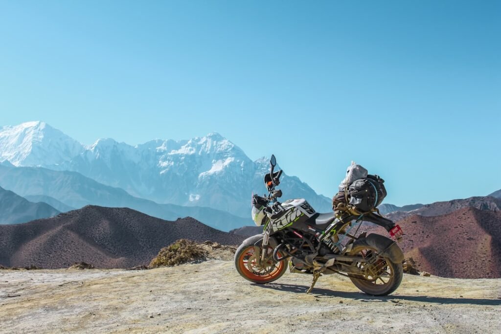A motorcycle loaded with touring gear parked on a scenic road, showcasing luggage systems and weather protection.