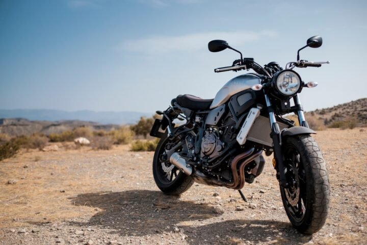 A motorcycle parked on a scenic road with a checklist and gear laid out beside it, symbolizing preparation for a long ride.